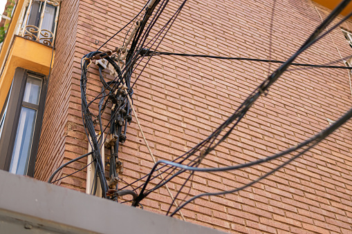 many electrical wires on the wall of a multi-story building