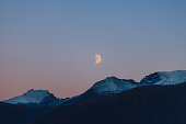 Big Moon in Pink Polar Sky Above Snowcapped Mountains