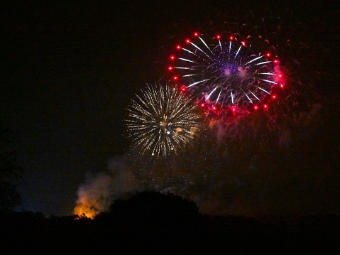 A vibrant and colorful fireworks illuminating a night sky over a classic red fire hydrant, creating a unique and eye-catching scene