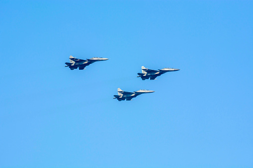 Fighter planes are flying as a Vic formation against isolated blue sky