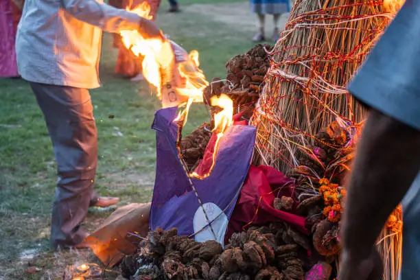 Photo of hand with newspaper burning handmade paper kite on hay a celebration of harvest festival of holi lohri