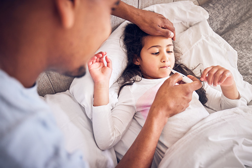 Thermometer, nursing and a man with a sick child for a fever, temperature check or virus. Family, house and a dad with a medical tool and a girl kid in the bed with a health problem or headache