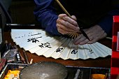 A Chinese craftsman designs a handmade folding fan.