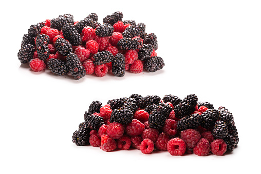Front view of a group of mixed berries like blueberries, blackberries and raspberries with some mint leaves isolated on white background. Studio shot taken with Canon EOS 6D Mark II and Canon EF 100 mm f/ 2.8