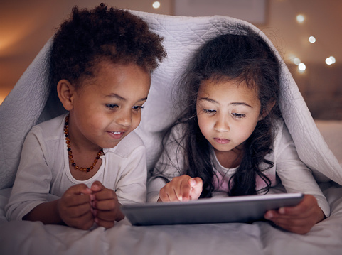 Games, night and children with a tablet in bed for cartoon, movie or streaming a show. Smile, blanket and girl kids with technology in the bedroom for the internet, education or online fun together