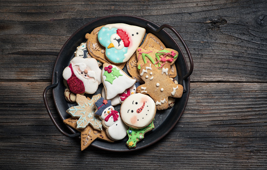 A plate of homemade iced Christmas cookies isolated on white.