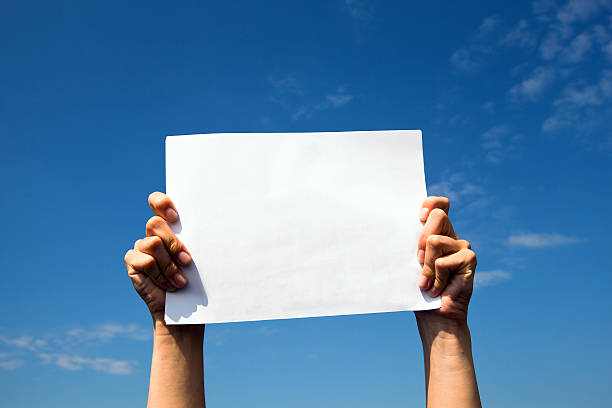istock Hands holding clean white sheet paper over the sky 179152593