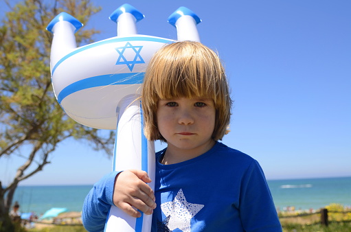 A little boy with an inflatable toy with the Flag of Israel and the Star of David. Concept: Israeli resorts, beaches, sea. Israel Independence Day, patriotism.