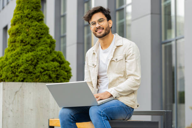 istock Indian man freelancer working on laptop computer sends messages reading email outdoors on bench 1791538593