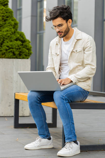 istock Indian man freelancer working on laptop computer sends messages reading email outdoors on bench 1791538604