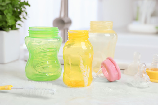 Baby bottles and nipples after washing on white countertop in kitchen