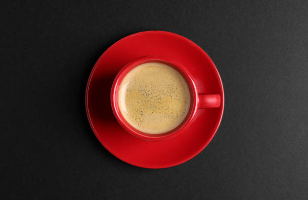 istock Red ceramic cup with hot aromatic coffee on black background, top view 1791560861