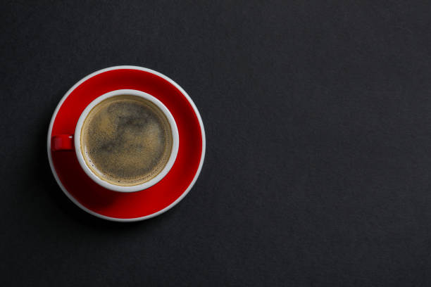 istock Red ceramic cup with hot aromatic coffee on black background, top view. Space for text 1791561197
