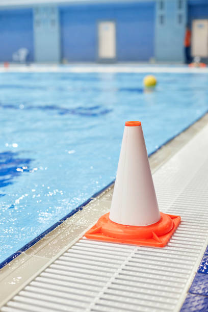 istock Plastic white and orange cone standing by pool with pure blue water 1791563946