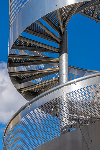 View of a circular metal staircase and blue sky behind