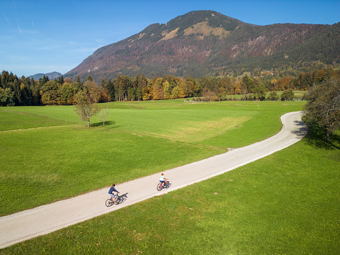 Couple of recreational cyclists touring and exploring a beautiful landscape by bicycle for leisure, aerial shot. Health and fitness concepts.