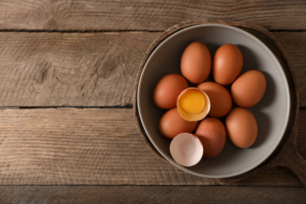 istock Bowl with raw chicken eggs on wooden table, top view. Space for text 1791584571