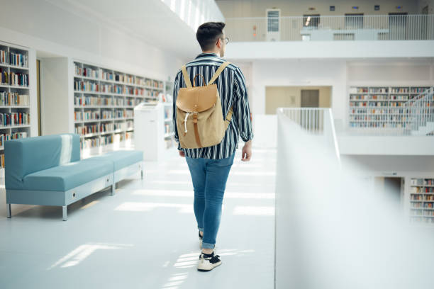 istock Backpack, library and education with a man student walking in a university bookstore for learning or development. Back, college and research with a male pupil taking a walk in search of a book 1791587379