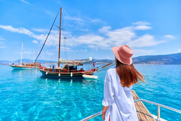 Traveler girl enjoys relaxing vacation on a boat in the turquoise sea