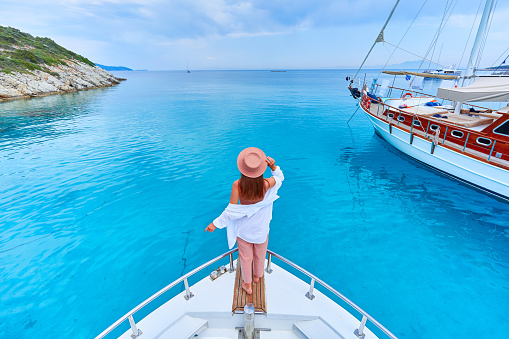 Traveler girl enjoys relaxing vacation on a luxury white private boat in the turquoise sea