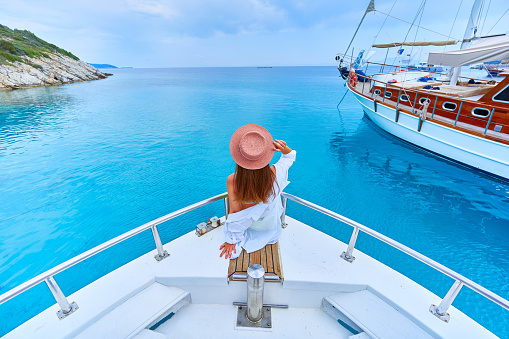 Free carefree rich traveler girl enjoys relaxing vacation on a luxury white private boat in the turquoise sea