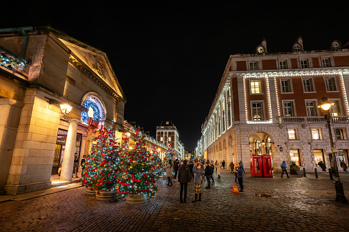 London, UK - Nov 8 2023: People admiring the Christmas trees and lights outside Covent Garden Market.