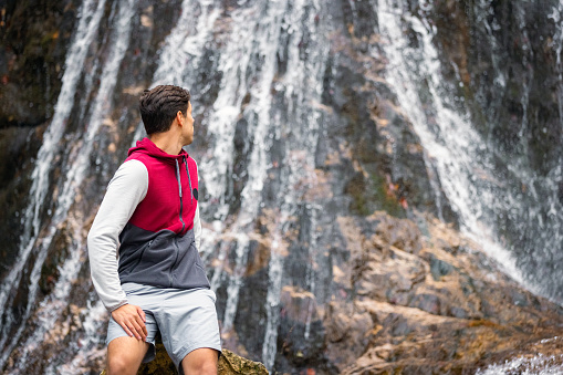 Man at the majestic waterfall and embracing enjoy the beauty of nature. Travel and adventure concepts.