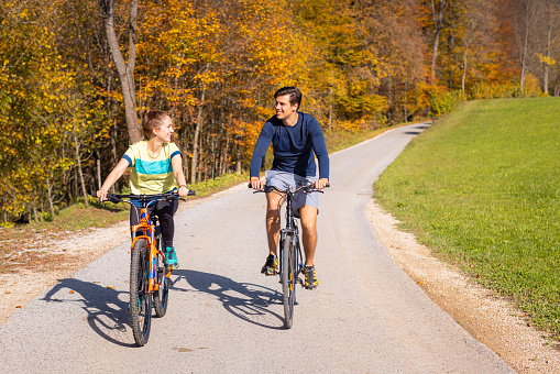 Young couple enjoying pleasant cycling in beautiful countryside during fall weekend trip. Leisure and outdoor activity concept.