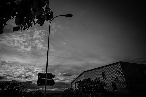 Striking black and white photograph of street signs against a backdrop of cloudy evening skies