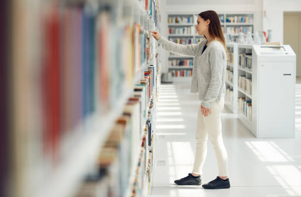 istock Woman, student and research in library for books, knowledge or learning at bookstore for education. Female looking at bookshelf in study for project, assignment or thesis for college scholarship 1791605692