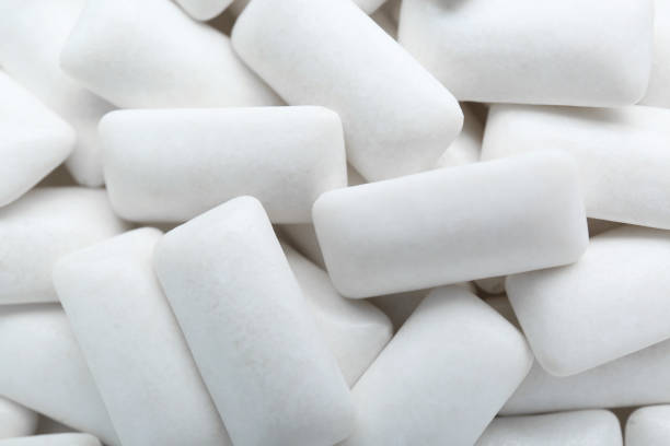 Tasty white chewing gums as background, top view