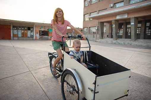 Mid adult woman riding her baby boy in the cargo bike.