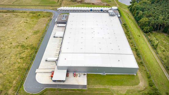 Loading bay, truck parking lot, unrecognisable industrial building, logistics - aerial view