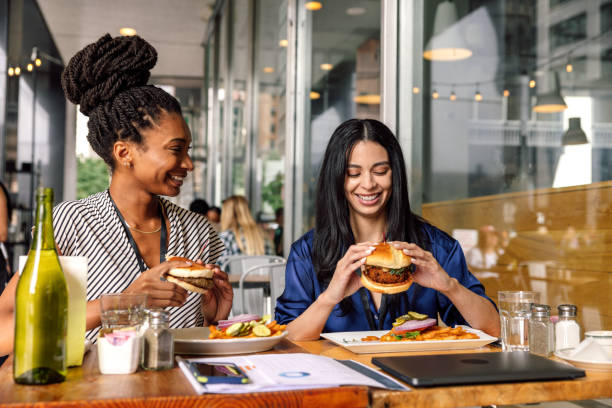 점심시간에 두 명의 여성을 위한 채식 버거를 곁들인 비즈니스 점심 식사 - dining burger outdoors restaurant 뉴스 사진 이미지