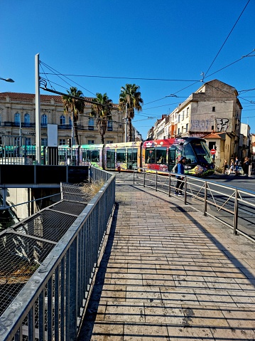 Montpellier with a modern Tramway. The Montpellier tramway has four lines with 84 stations.  The image shows a tram stopping at a station, captured during autumn season.