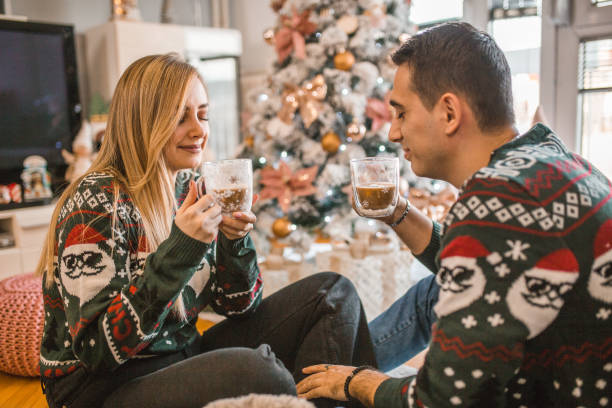 istock A smiling man and a woman drink coffee while sitting next to a Christmas tree 1791630959