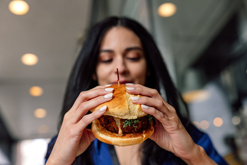 Businesswoman at lunch break enjoying a veggie burger.