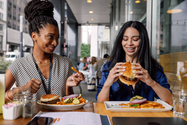 istock Two businesswomen eating hamburger at lunch break 1791632015