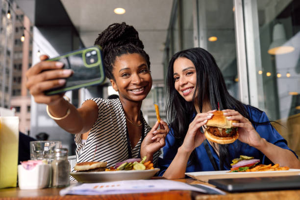Two businesswomen eating hamburger at lunch break