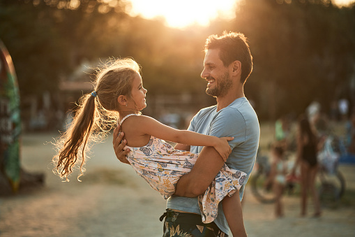 Beautiful father and daughter enjoying sunset on a beach vacation.