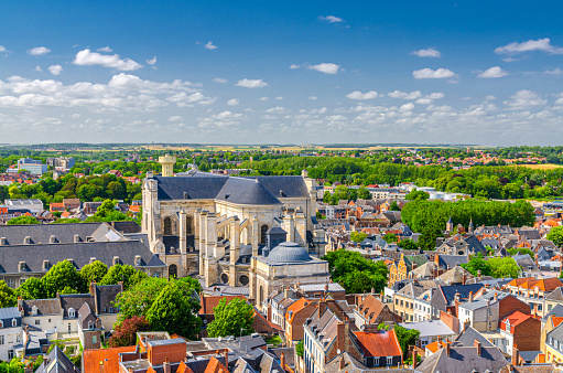 Aerial panoramic view of Arras city historical town centre, Arras Cathedral of Our Lady and Saint Vaast catholic church, green parks and fields on horizon, blue sky, Pas-de-Calais department, France