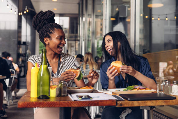 Two businesswomen eating hamburger at lunch break
