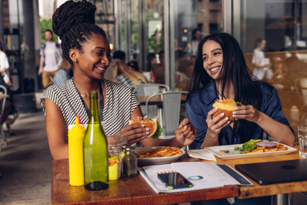 istock Two businesswomen eating hamburger at lunch break 1791642662