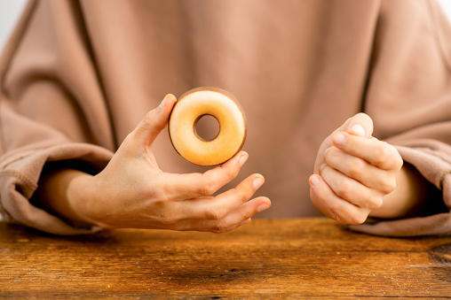 Donut delight: Delicate fingers cradle a delicious pastry ring, promising a sweet experience
