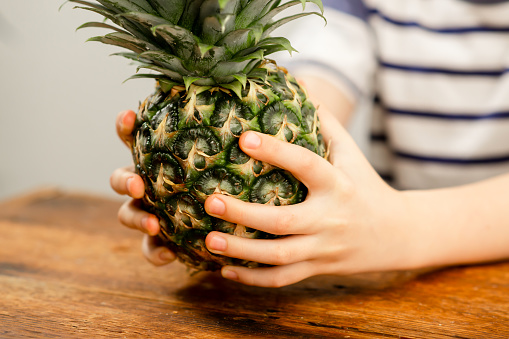 Exotic fruit joy: Child's hands holding a full pineapple, a taste of the tropics
