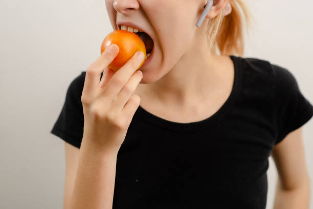 indulgencia juvenil: una mujer joven y esbelta disfruta de una ciruela amarilla madura, abrazando la bondad afrutada de su bocadillo - plum yellow eating beauty and health fotografías e imágenes de stock