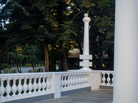 White decorative column in the park. Park decoration. Architecture of the resort town. White short openwork column