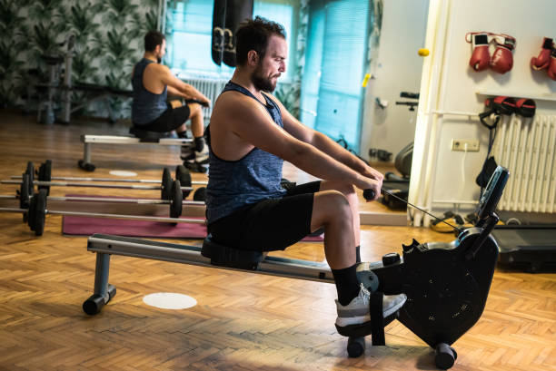 les hommes font de l’exercice d’aviron dans le sport horizontal de gymnase - weight bench flash photos et images de collection