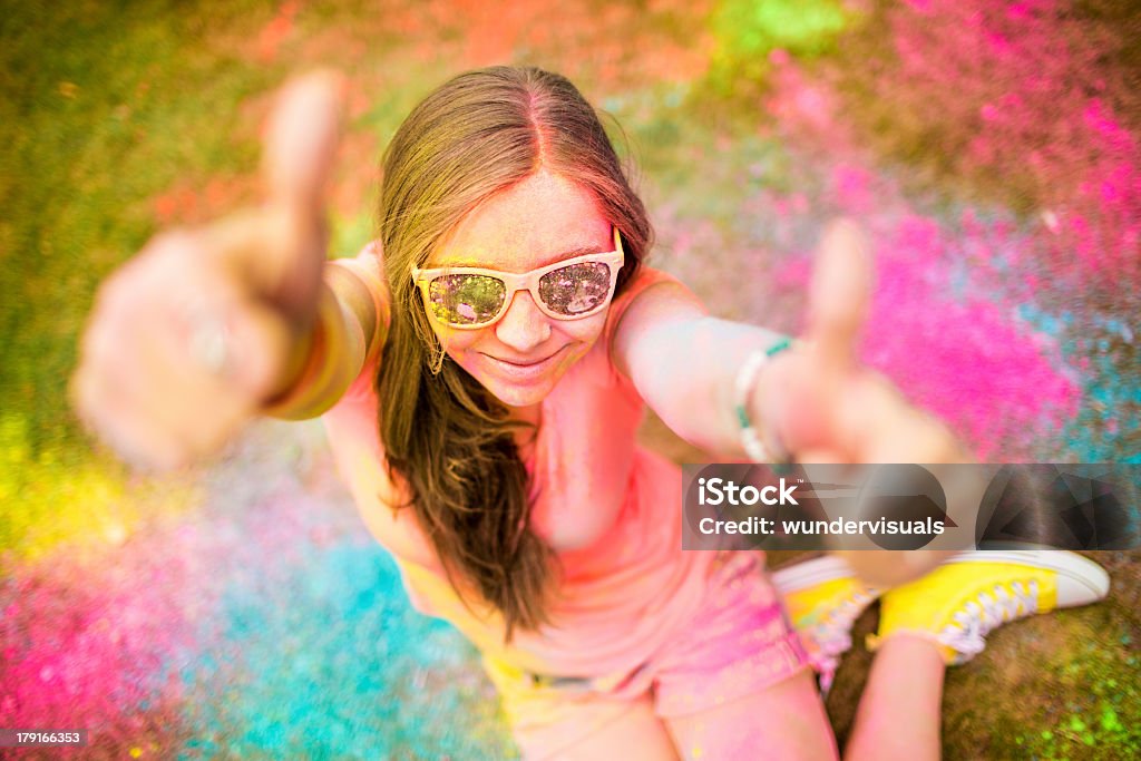 Hipster de menina dando polegares para cima no Festival Holi colorido - Foto de stock de Adolescente royalty-free