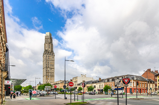 Amiens, France, July 3, 2023: street view with Tour Perret tower residential skyscraper building, riding cars traffic, road signs and walking people in historical city centre, Hauts-de-France Region